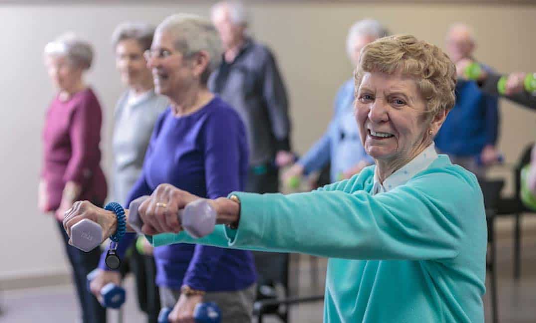Woman smiling holing weight out in front of her during exercise class