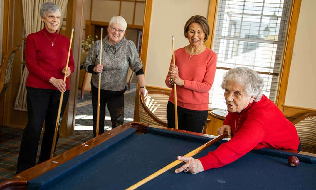 group of people watching women shoot pool